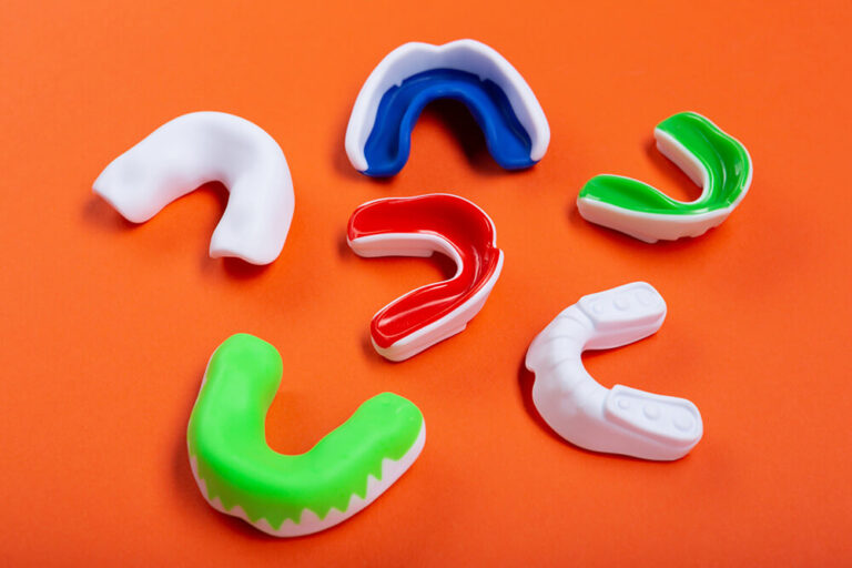 different types of mouthguards on an orange background